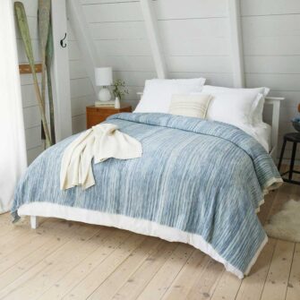 bed made up with blue blanket with white throw