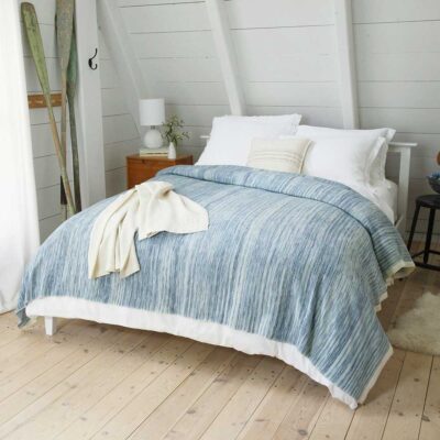 bed made up with blue blanket with white throw