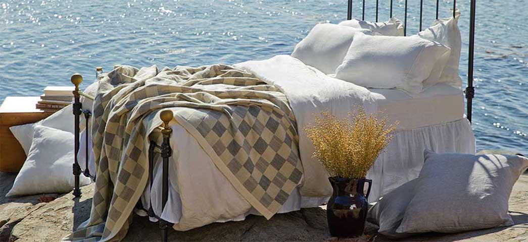 bed with checked blanket by sea shore
