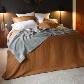 Swans Island Company's Relaxed Linen Duvet Set. 100% French linen made in the USA, breathable, soft and regulates temperature as you sleep. Shown here in Golden Honey with Ivory Classic Linen Sheet Set and a signature Swans Island handwoven Heritage blanket.