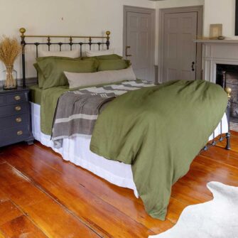 Swans Island Company's Relaxed Linen Bedding Bundle. 100% French linen made in the USA, breathable, soft and regulates temperature as you sleep. Shown here in Rosemary with our handwoven wool Island Blanket in brown with grey.