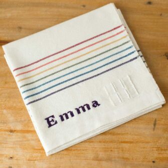 Swans Island Company's Double Rainbow Baby Blanket. Handwoven in Maine with soft 100% organic merino wool. Comes in a signature linen box, perfect for gifting. Custom monogramming is available. Shown here with the name Emma embroidered in Logwood Purple.