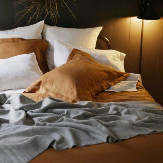 Swans Island Company's Golden Hour Bedding Bundle - Includes 1 Classic Linen Sheet Set in Ivory + 1 Relaxed Linen Duvet Set in Golden Honey. 100% French linen made in the USA, breathable, soft and regulates temperature as you sleep. Shown here with a signature Swans Island handwoven Heritage blanket.