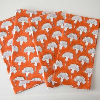 Swans Island Seema Napkins by Soil to Studio. Block printed by hand in India with bright playful patterns. Shown here in Poppy Orange with natural and blue flowers. Set of four.