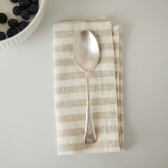 Swans Island Company's linen napkins by Linen Tales, made with 100% European Linen Oeko-Tex® and EUROPEN FLAX® certified. Made with stonewashed soft linen with mitered corners for a crisp edge. Shown here in Natural White Stripe.