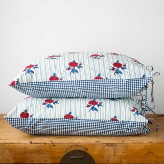 Swans Island Company's Supriya Shams by Soil to Studio. Block printed by hand in India with bright playful patterns. Shown here in Aqua with red roses.