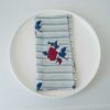 Swans Island Company's Supriya napkins by Soil to Studio. Block printed by hand in India with bright playful patterns. Shown here in natural with aqua vine and red/teal rose pattern.