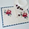 Swans Island Company's Babita Placemat by Soil to Studio. Block printed by hand in India with bright playful patterns. Shown here in Natural with Red rose floral and blue scalloped edge patterns..
