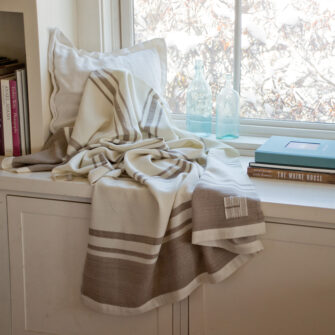 Casa Branca x Swans Island - Branca Grande Throw . 100% soft merino wool with hand-dyed stripes and ivory silk binding. Handwoven in Maine. Shown here in Biscotti.